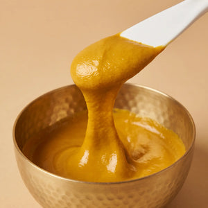 Creamy turmeric paste mixed in a hammered brass bowl